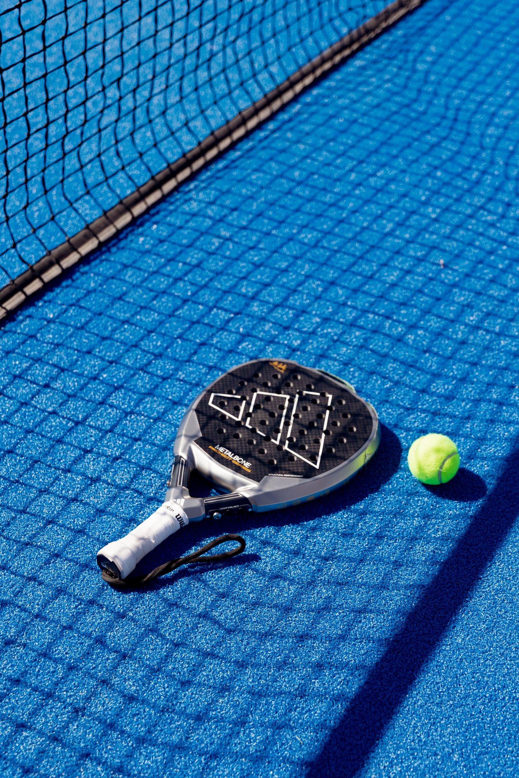 Pala y pelota sobre una cancha azul